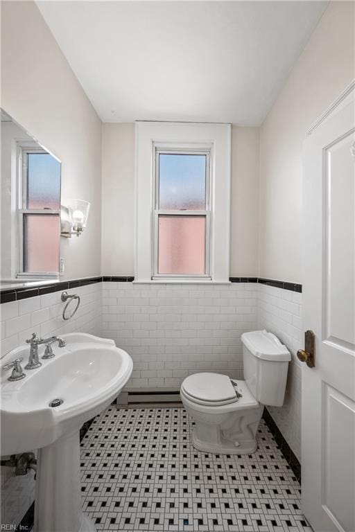 bathroom with tile patterned floors, toilet, tile walls, and a baseboard heating unit