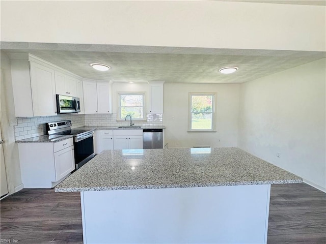 kitchen featuring white cabinetry, a center island, appliances with stainless steel finishes, and light stone countertops