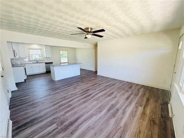 unfurnished living room featuring ceiling fan, sink, a textured ceiling, and dark hardwood / wood-style flooring