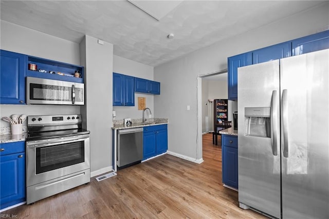 kitchen featuring blue cabinetry, dark wood-type flooring, sink, light stone counters, and stainless steel appliances