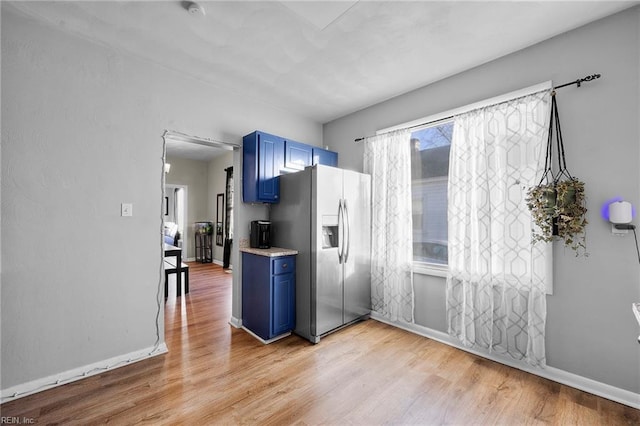 kitchen with blue cabinetry, stainless steel fridge, and light hardwood / wood-style floors