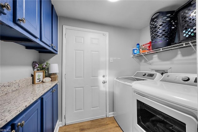 clothes washing area with light hardwood / wood-style floors, cabinets, and washing machine and clothes dryer