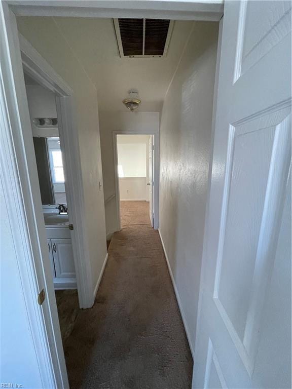 hallway with sink and dark carpet