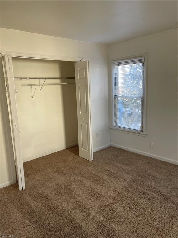 unfurnished bedroom featuring a closet and dark colored carpet