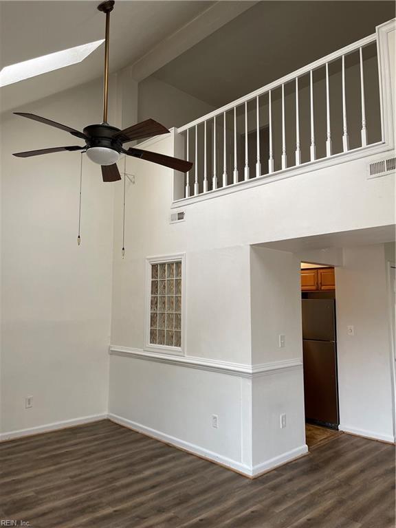 unfurnished living room with ceiling fan, dark hardwood / wood-style floors, high vaulted ceiling, and beam ceiling