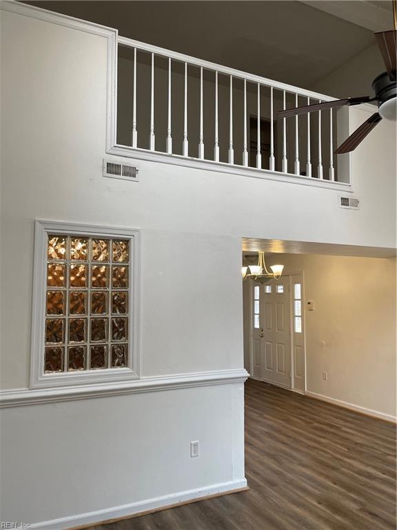 entryway featuring a towering ceiling, wood-type flooring, and ceiling fan with notable chandelier