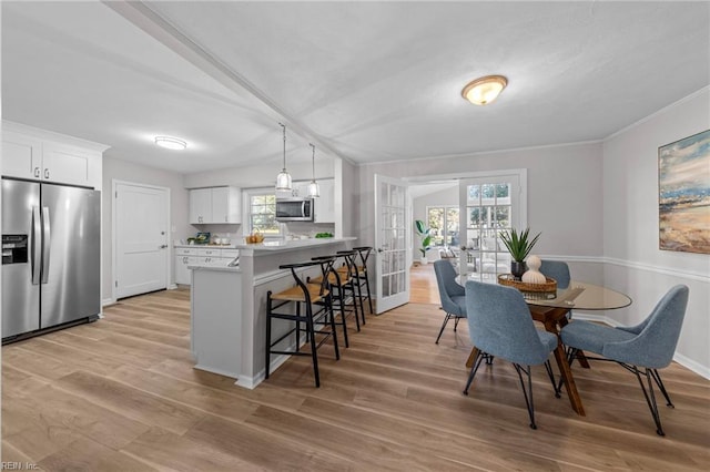 dining room with crown molding, light hardwood / wood-style flooring, and french doors