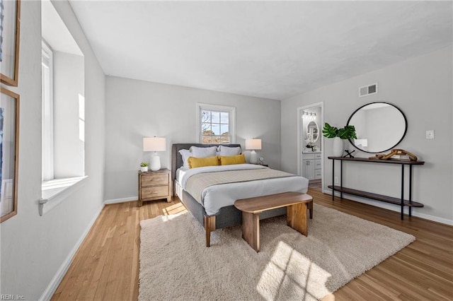 bedroom featuring connected bathroom and light hardwood / wood-style flooring