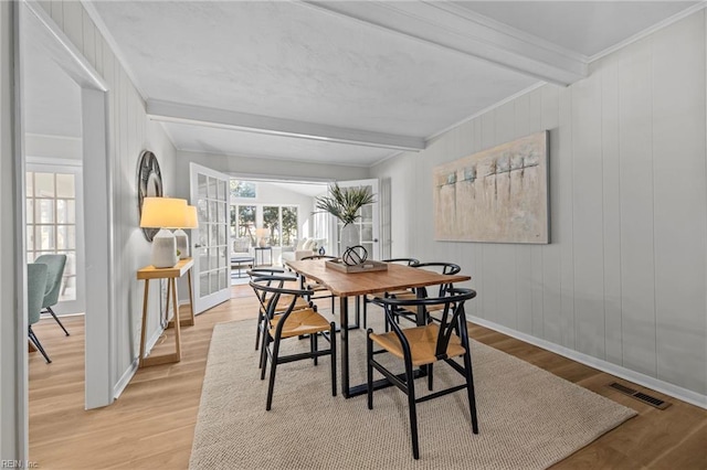 dining room with a healthy amount of sunlight, crown molding, light hardwood / wood-style floors, and beamed ceiling