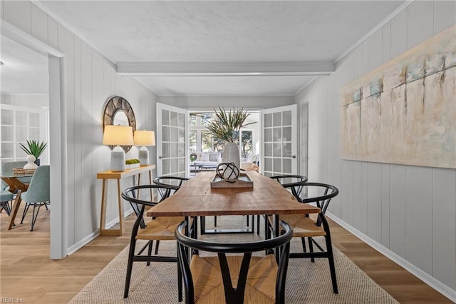 dining room with ornamental molding, beam ceiling, and light wood-type flooring