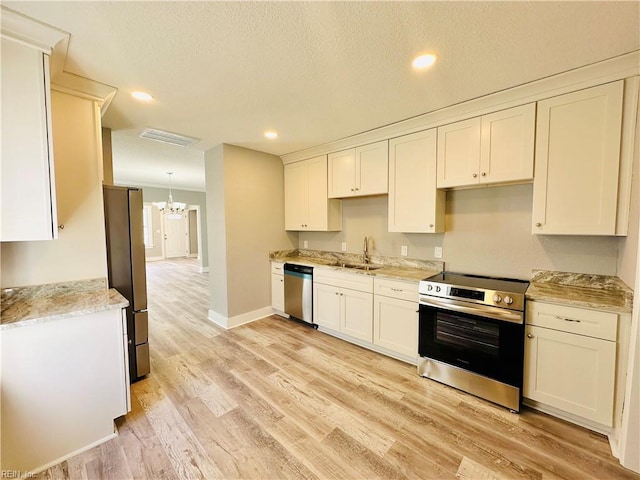 kitchen featuring white cabinetry, sink, light hardwood / wood-style floors, and appliances with stainless steel finishes