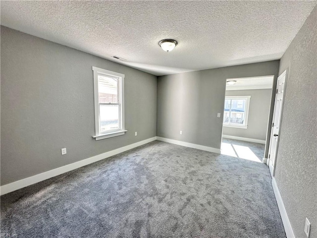 carpeted spare room featuring a textured ceiling