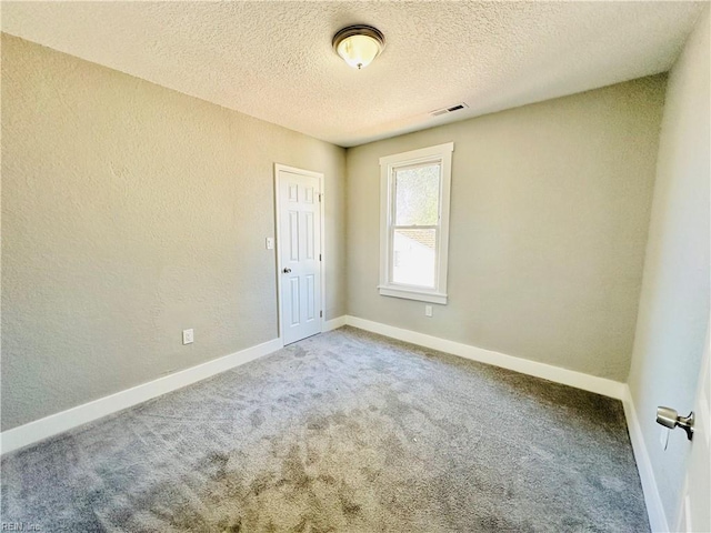 empty room featuring a textured ceiling and carpet