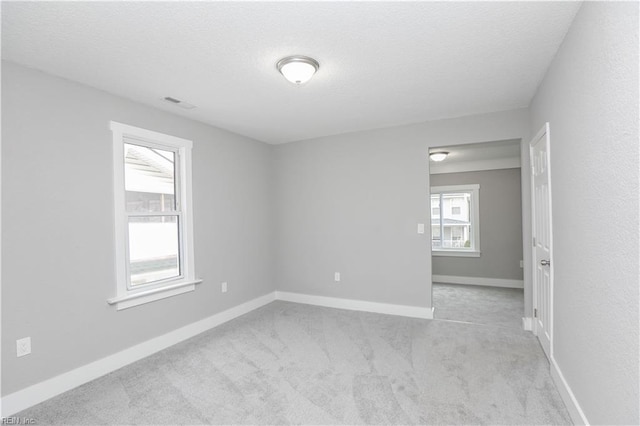 empty room with light colored carpet and a textured ceiling