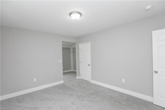 unfurnished room with light colored carpet and a textured ceiling