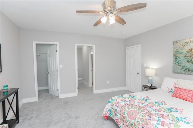 carpeted bedroom featuring a spacious closet, connected bathroom, ceiling fan, and a closet