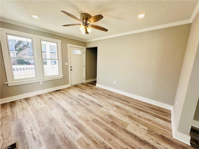 interior space with ornamental molding, ceiling fan, a textured ceiling, and light wood-type flooring