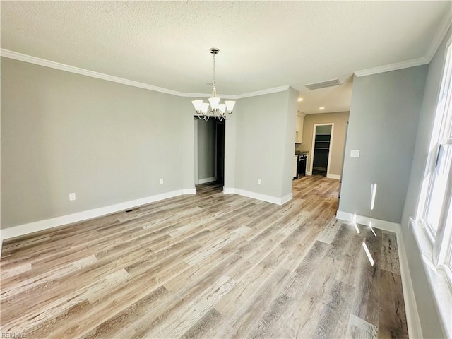 spare room featuring an inviting chandelier, crown molding, light hardwood / wood-style floors, and a textured ceiling