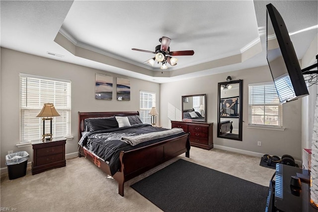 bedroom featuring a raised ceiling, crown molding, light carpet, and ceiling fan