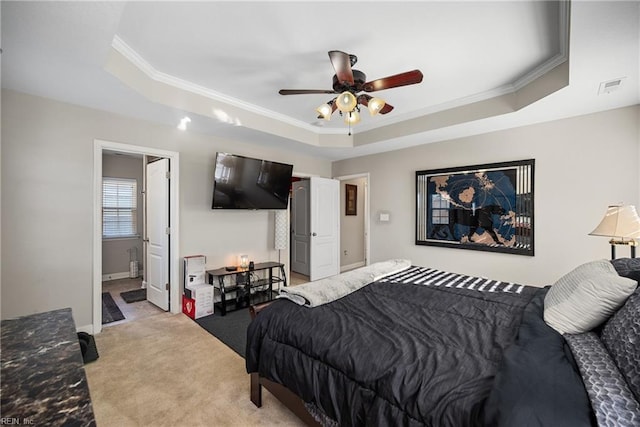 bedroom with ceiling fan, a tray ceiling, and ensuite bath