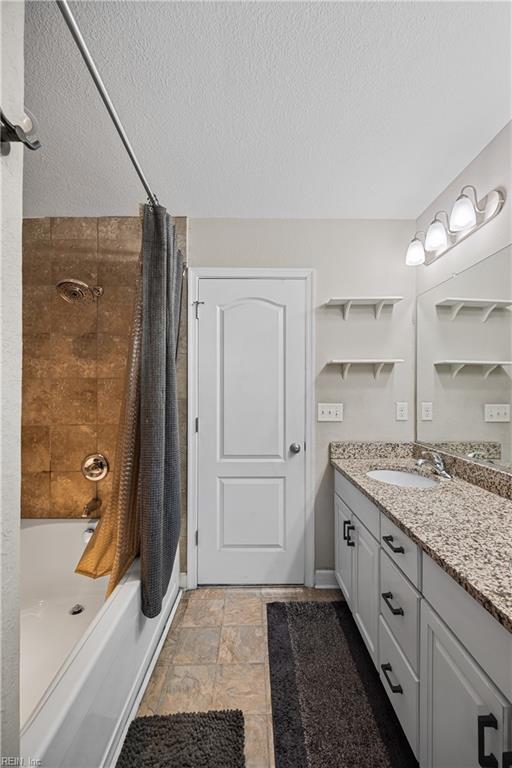 bathroom with vanity, a textured ceiling, and shower / bath combo with shower curtain