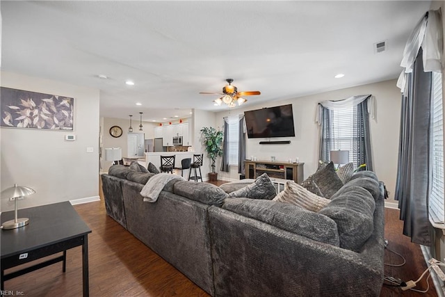 living room with dark wood-type flooring and ceiling fan