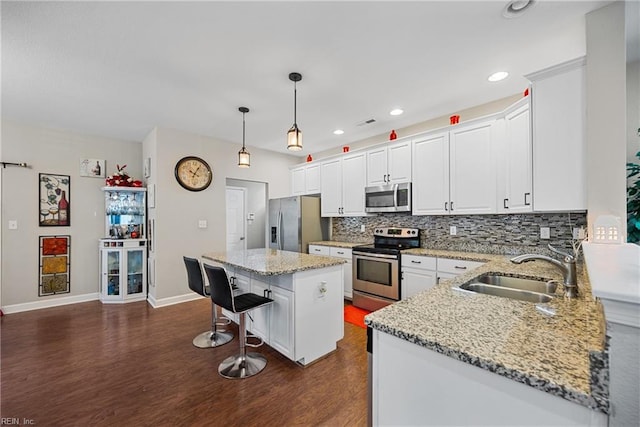 kitchen with sink, stainless steel appliances, white cabinets, and a kitchen island