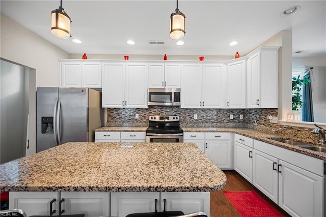 kitchen featuring hanging light fixtures, appliances with stainless steel finishes, and white cabinets