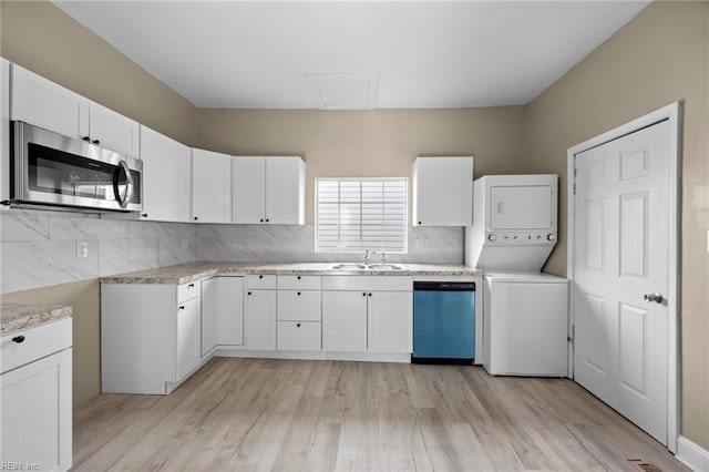 kitchen featuring tasteful backsplash, white cabinetry, sink, stacked washer and dryer, and stainless steel appliances