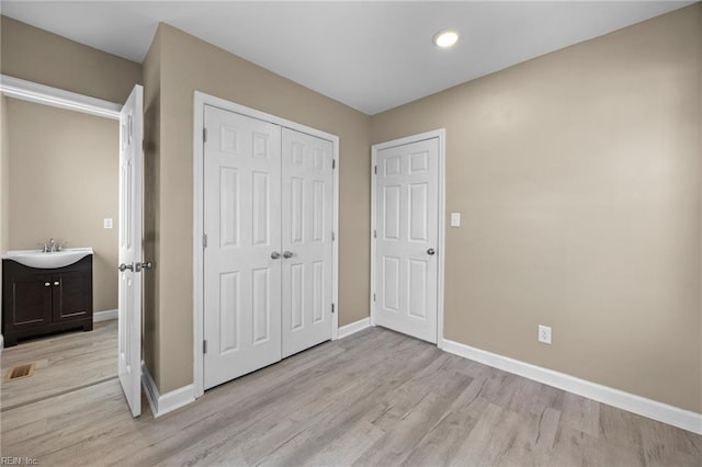 unfurnished bedroom featuring sink, light hardwood / wood-style floors, and a closet