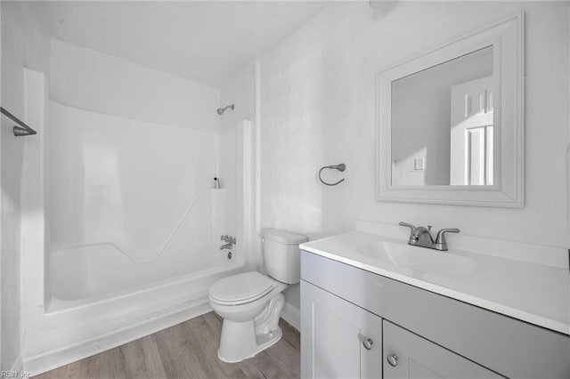 full bathroom with hardwood / wood-style flooring, vanity, washtub / shower combination, and toilet