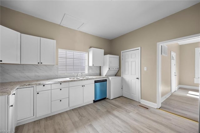 kitchen with sink, white cabinetry, tasteful backsplash, dishwasher, and stacked washer / dryer