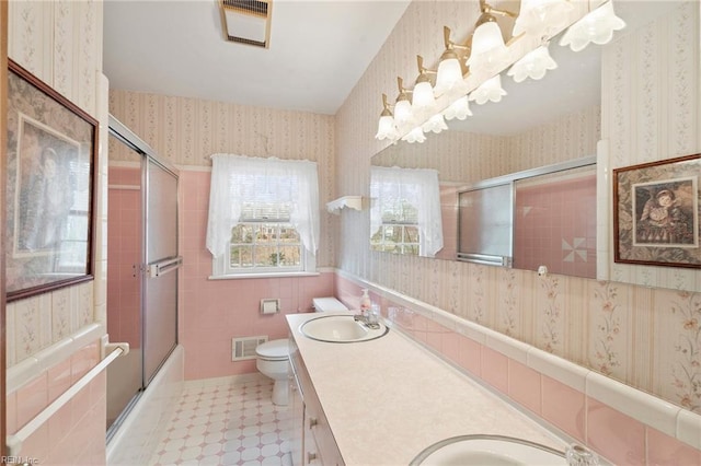 full bathroom with vanity, tile walls, shower / bath combination with glass door, and toilet