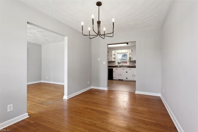 unfurnished dining area featuring sink, hardwood / wood-style flooring, and a chandelier