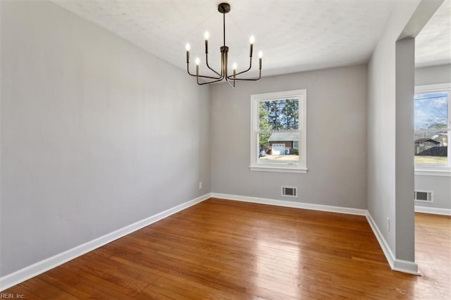 empty room featuring hardwood / wood-style flooring and a notable chandelier