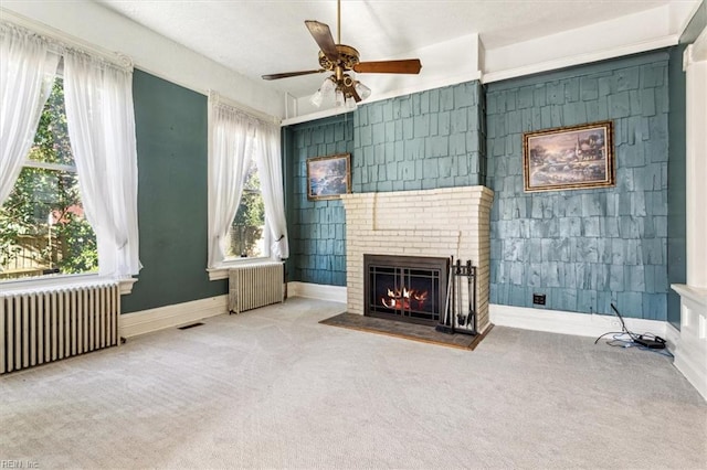 unfurnished living room featuring radiator, a wealth of natural light, and carpet