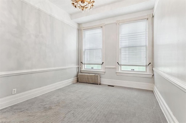 spare room with light carpet, a notable chandelier, and radiator heating unit