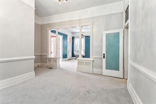 empty room with light colored carpet and decorative columns