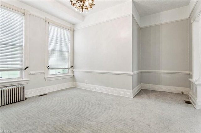 spare room featuring a notable chandelier, radiator heating unit, and carpet flooring