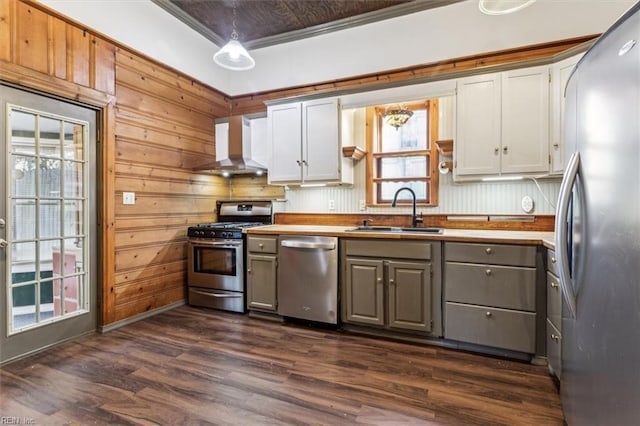 kitchen with wall chimney exhaust hood, sink, gray cabinets, pendant lighting, and stainless steel appliances