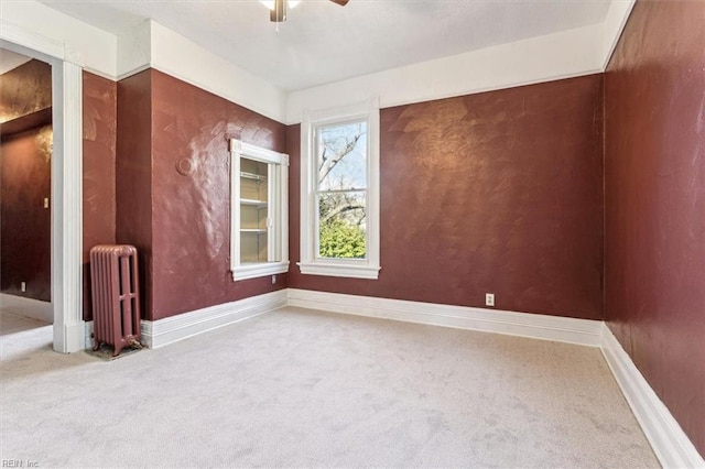 carpeted empty room with ceiling fan and radiator heating unit