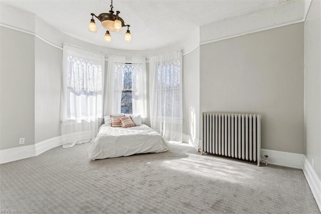 bedroom with carpet floors, radiator heating unit, and an inviting chandelier