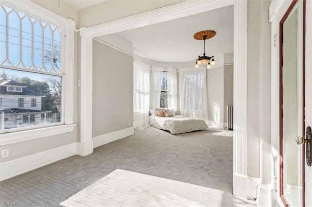 carpeted bedroom featuring an inviting chandelier, radiator heating unit, and multiple windows