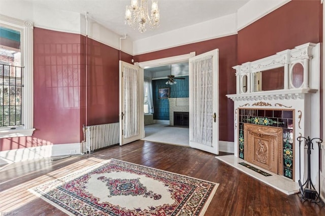 interior space with a tile fireplace, radiator, an inviting chandelier, and dark hardwood / wood-style floors