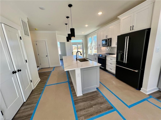 kitchen with sink, black appliances, hanging light fixtures, an island with sink, and white cabinets