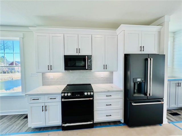 kitchen featuring white cabinetry, light hardwood / wood-style flooring, light stone countertops, decorative backsplash, and black appliances