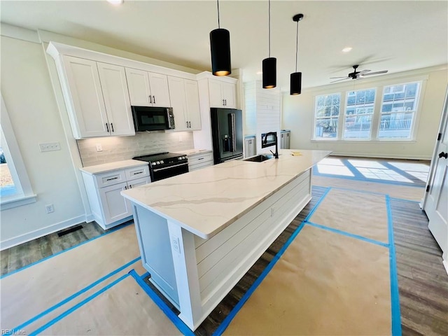 kitchen featuring decorative light fixtures, white cabinets, a kitchen island with sink, black appliances, and light stone countertops