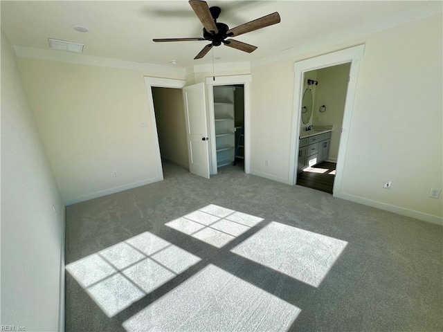 unfurnished bedroom with ceiling fan, light colored carpet, ensuite bath, and a closet