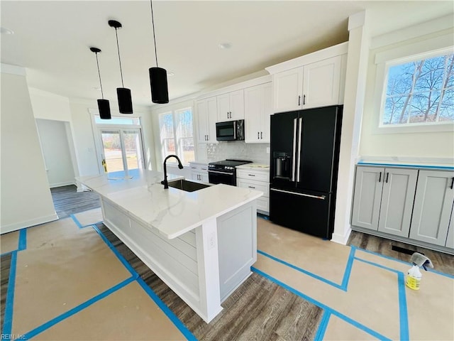 kitchen with pendant lighting, sink, white cabinets, a kitchen island with sink, and black appliances