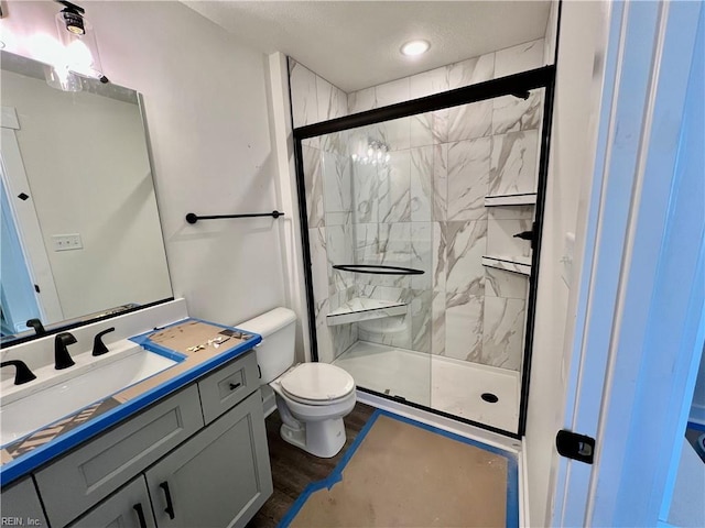 bathroom with vanity, toilet, a shower with shower door, and hardwood / wood-style floors